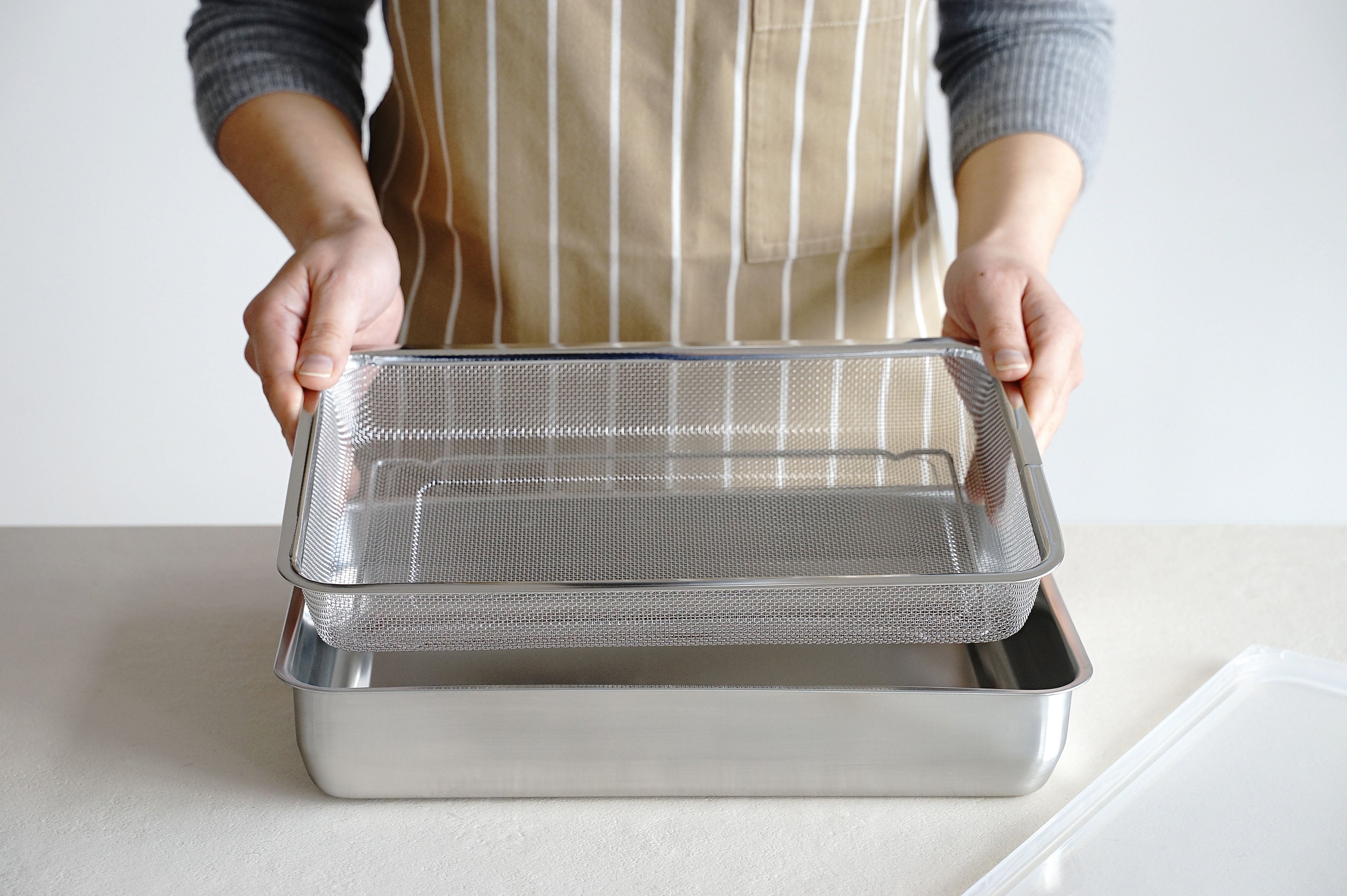 KAJIdonya stainless steel mesh basket and cooking tray being assembled in a kitchen.
